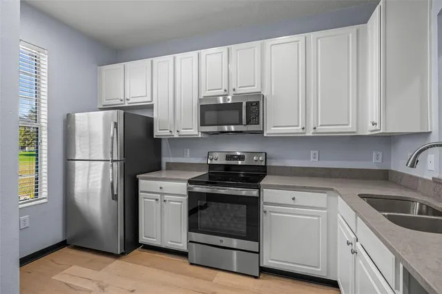 a kitchen with cabinets stainless steel appliances and wooden floor