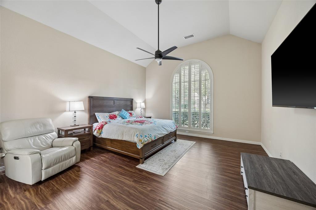 2865 Ridge View Road Frisco, TX 75034 - Photo 17 of 38 Vaulted ceiling with a ceiling fan, arched window with plantation shutters, wood-finish flooring, and neutral wall paint