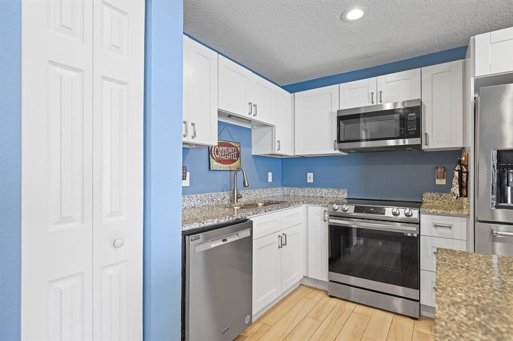 1001 Alpine Drive Brandon, FL 33510 - Photo 8 of 29 a kitchen with stainless steel appliances granite countertop white cabinets a sink a stove a microwave and cabinetry