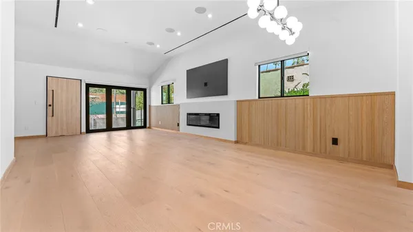 an empty room with windows fireplace and cabinet