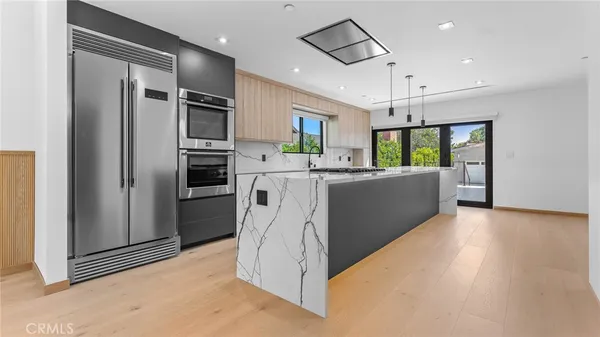 a kitchen with stainless steel appliances granite countertop a refrigerator a oven a sink with a dining table and chairs