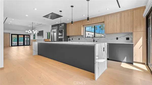 a large kitchen with kitchen island a large counter top a sink a stove and wooden floors