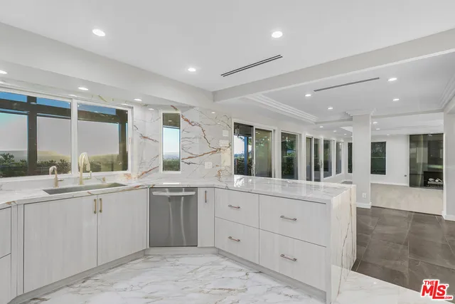 a large white kitchen with kitchen island a sink a stove and a refrigerator