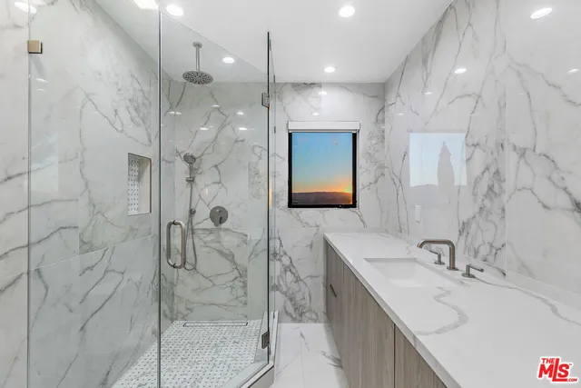 a view of an empty room with wooden floor kitchen view and a window