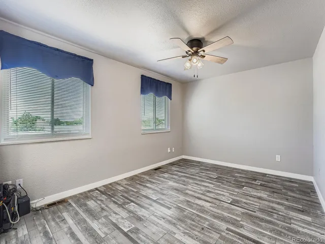 a view of an empty room with window and chandelier fan