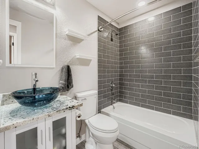 a bathroom with a granite countertop toilet sink and mirror