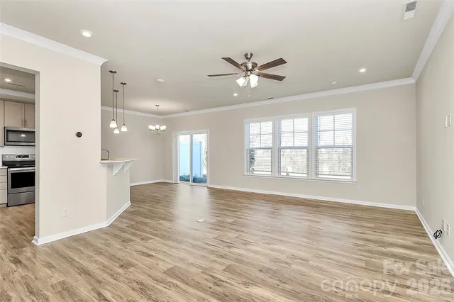 a view of an empty room with a window and wooden floor
