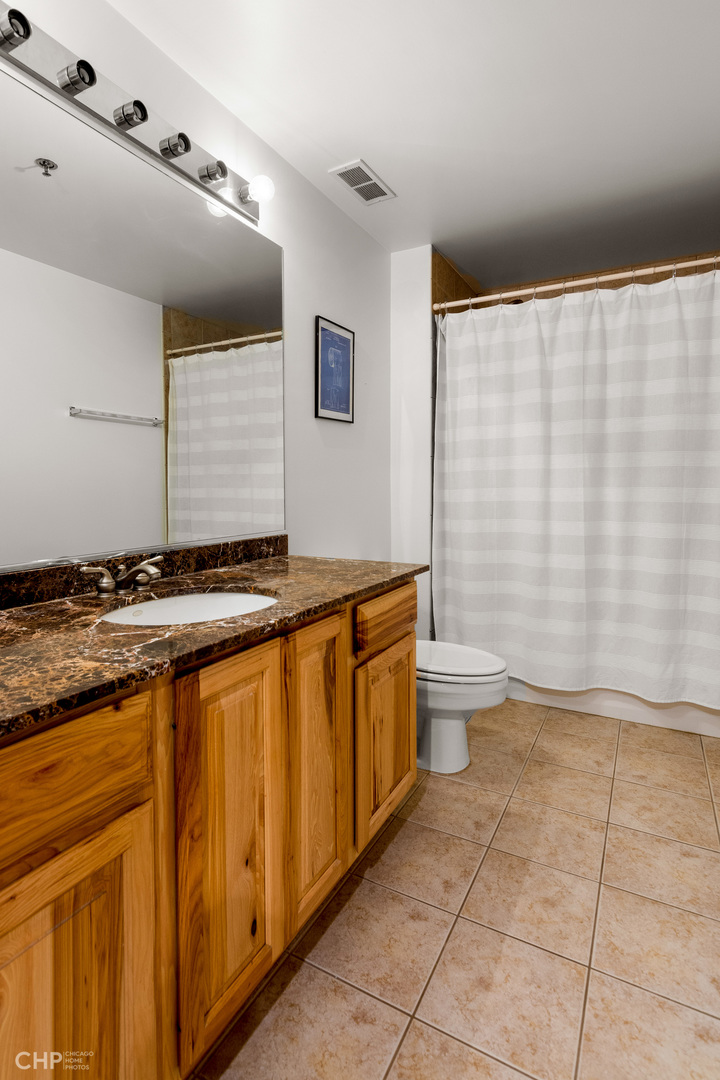 6 South Laflin Street, Unit 721 Chicago, IL 60607 - Photo 16 of 20 a bathroom with a granite countertop sink and a toilet