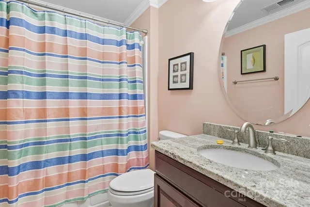 a bathroom with a granite countertop sink a toilet a mirror and shower curtain