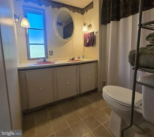 a bathroom with a granite countertop toilet sink and mirror