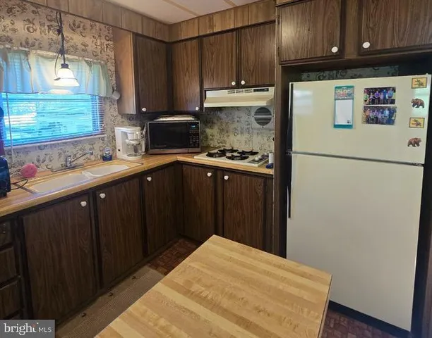 a kitchen with stainless steel appliances granite countertop a refrigerator a sink dishwasher and wooden cabinets with a granite countertops