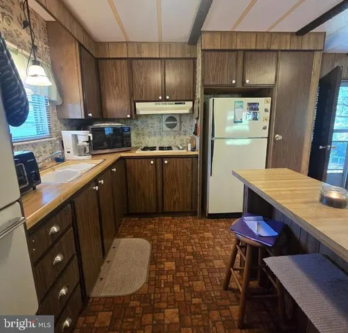 a kitchen with stainless steel appliances granite countertop a sink a stove a refrigerator cabinets and dining table