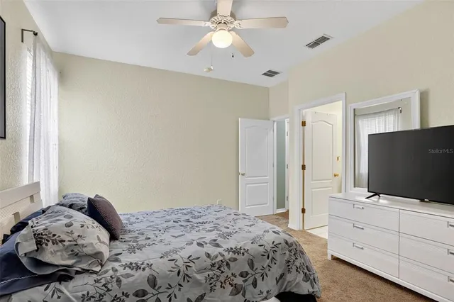 a bedroom with a bed and a flat tv screen on dresser
