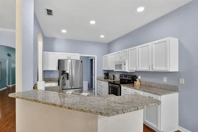 a kitchen with stainless steel appliances granite countertop a sink a stove and a refrigerator