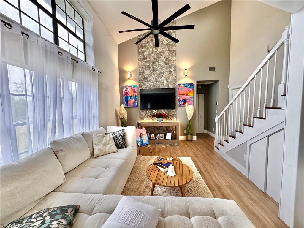 3220 63rd Street Southwest Naples, FL 34105 - Photo 8 of 36 Living room with high vaulted ceiling, light wood-style floors, ceiling fan, and stairway