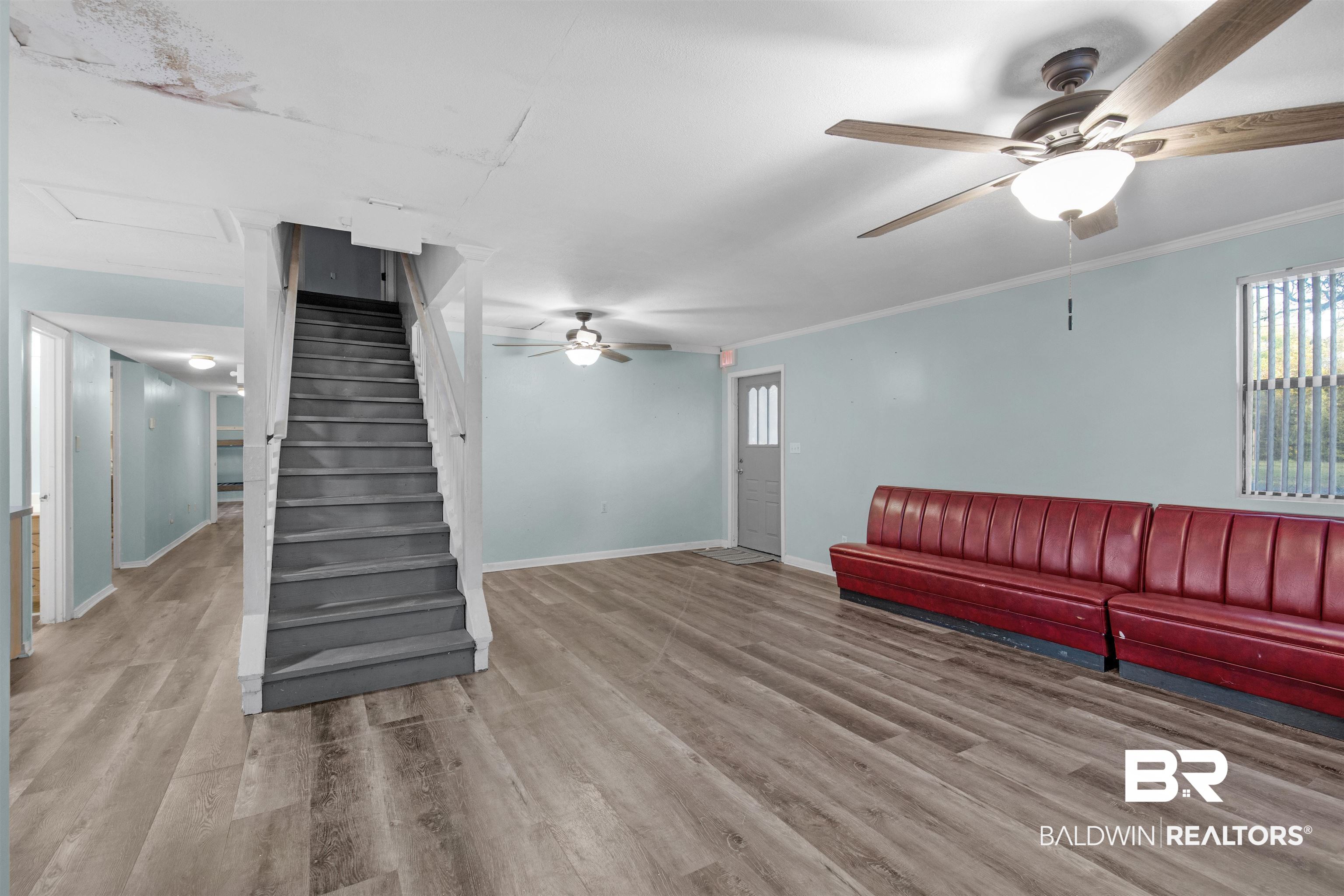 28290 Canal Road Orange Beach, AL 36561 - Photo 6 of 32 Unfurnished living room with wood finished floors, ceiling fan, baseboards, and stairs