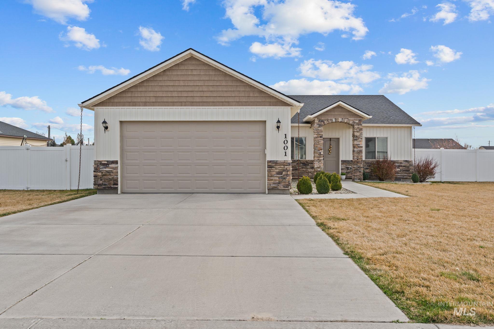 1001 13th Street Rupert, ID 83350 - Photo 1 of 40 View of front facade featuring stone siding, driveway, an attached garage, a gate, and board and batten siding