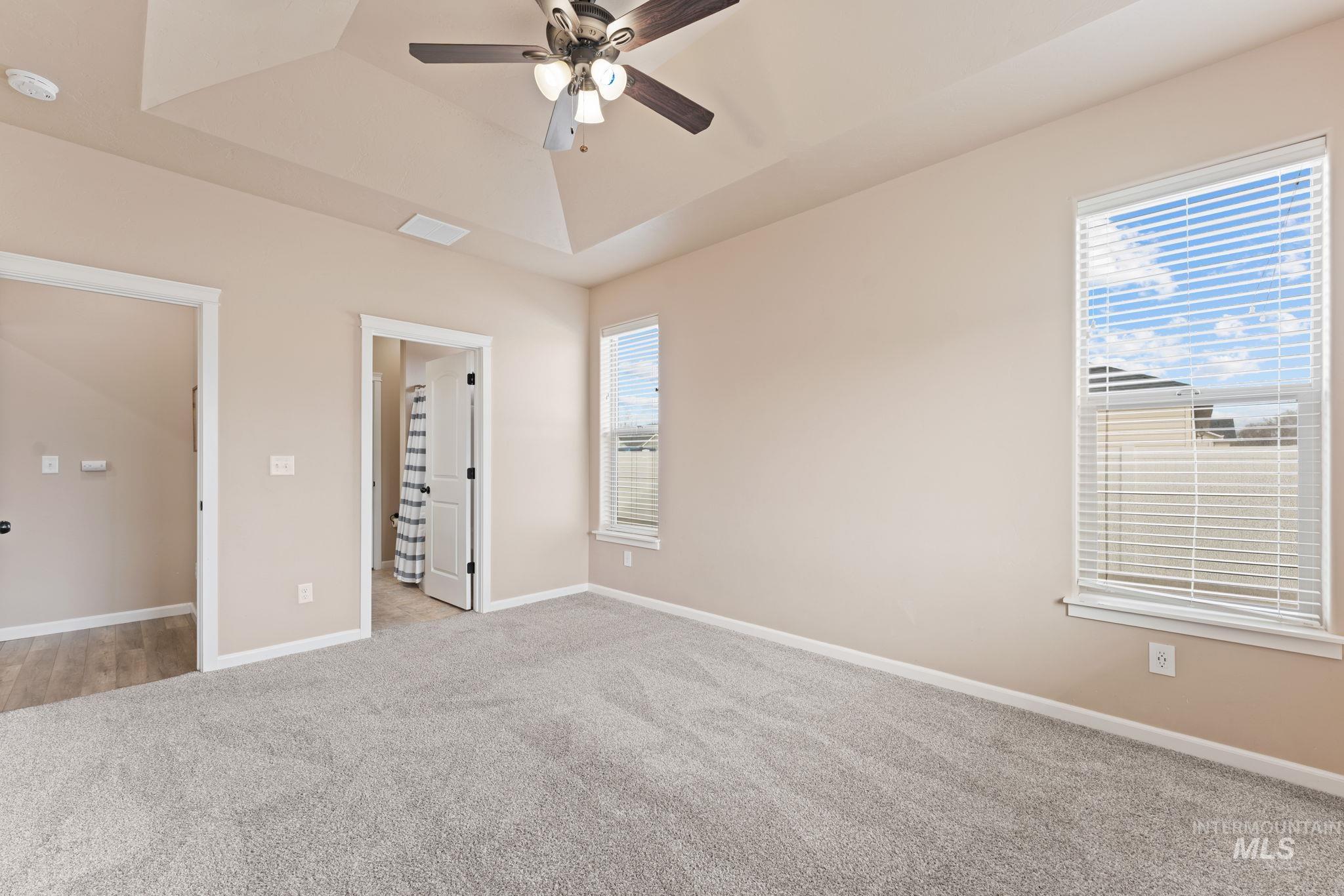 1001 13th Street Rupert, ID 83350 - Photo 16 of 40 Unfurnished bedroom with light colored carpet, a ceiling fan, and a raised ceiling