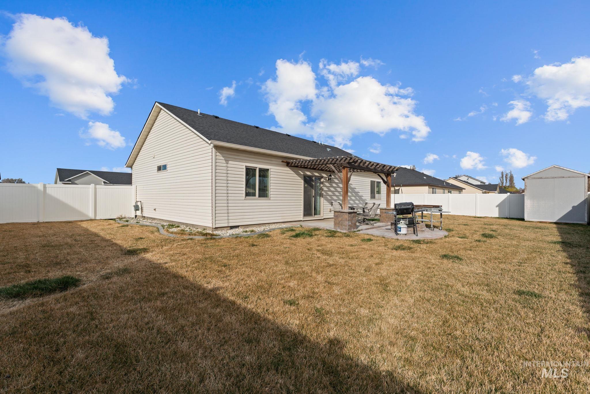 1001 13th Street Rupert, ID 83350 - Photo 30 of 40 Back of house with a patio, a pergola, a fenced backyard, and a storage shed