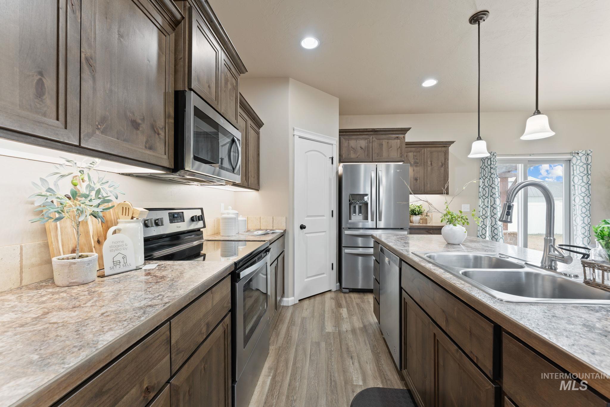 1001 13th Street Rupert, ID 83350 - Photo 10 of 40 Kitchen with stainless steel appliances, light countertops, decorative light fixtures, and dark wood finish cabinetry