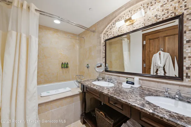a bathroom with a granite countertop sink a mirror and a bathtub