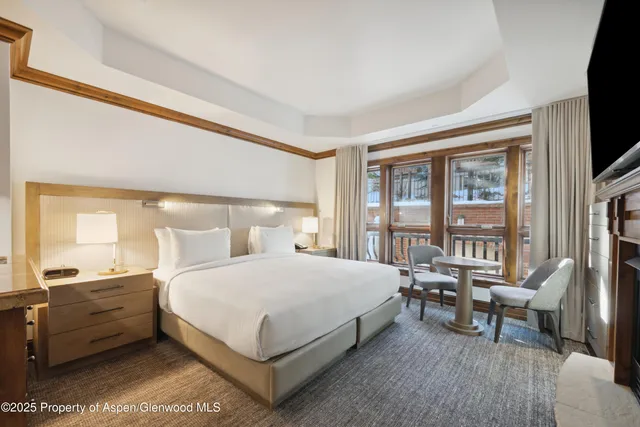 a bedroom with a bed and large windows