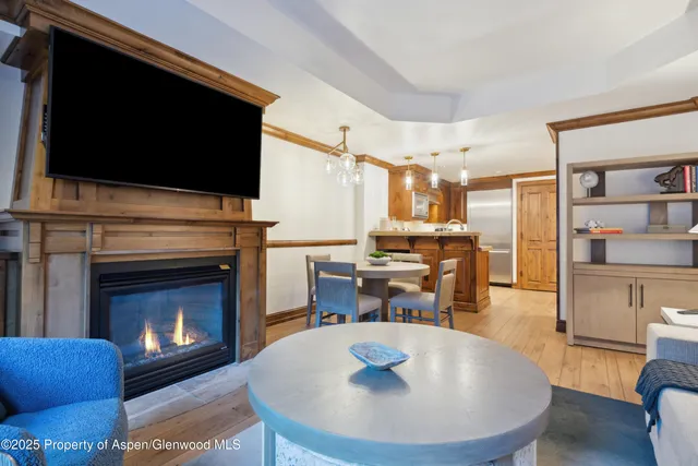 a living room with stainless steel appliances furniture a fireplace a flat screen tv and view kitchen