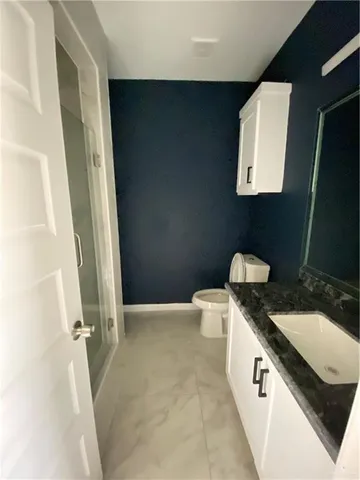 a bathroom with a granite countertop sink a toilet and a mirror