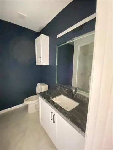 a bathroom with a granite countertop sink a mirror and a toilet