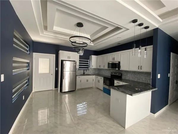 a kitchen with stainless steel appliances granite countertop a sink a stove and a refrigerator