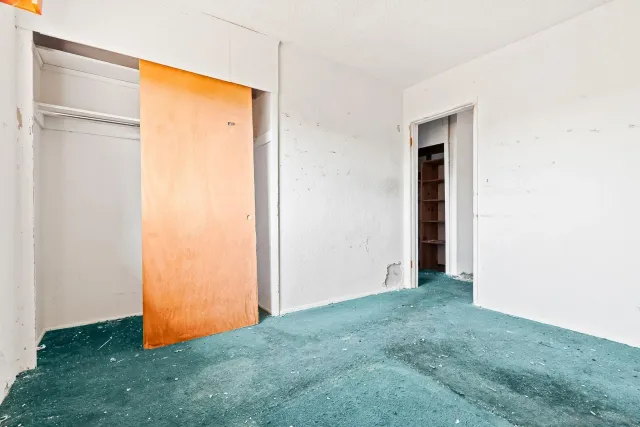 a view of an empty room with closet and a window