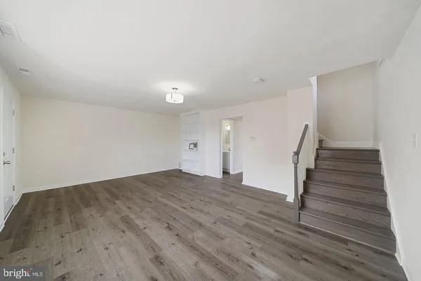 a view of an empty room with wooden floor and stairs
