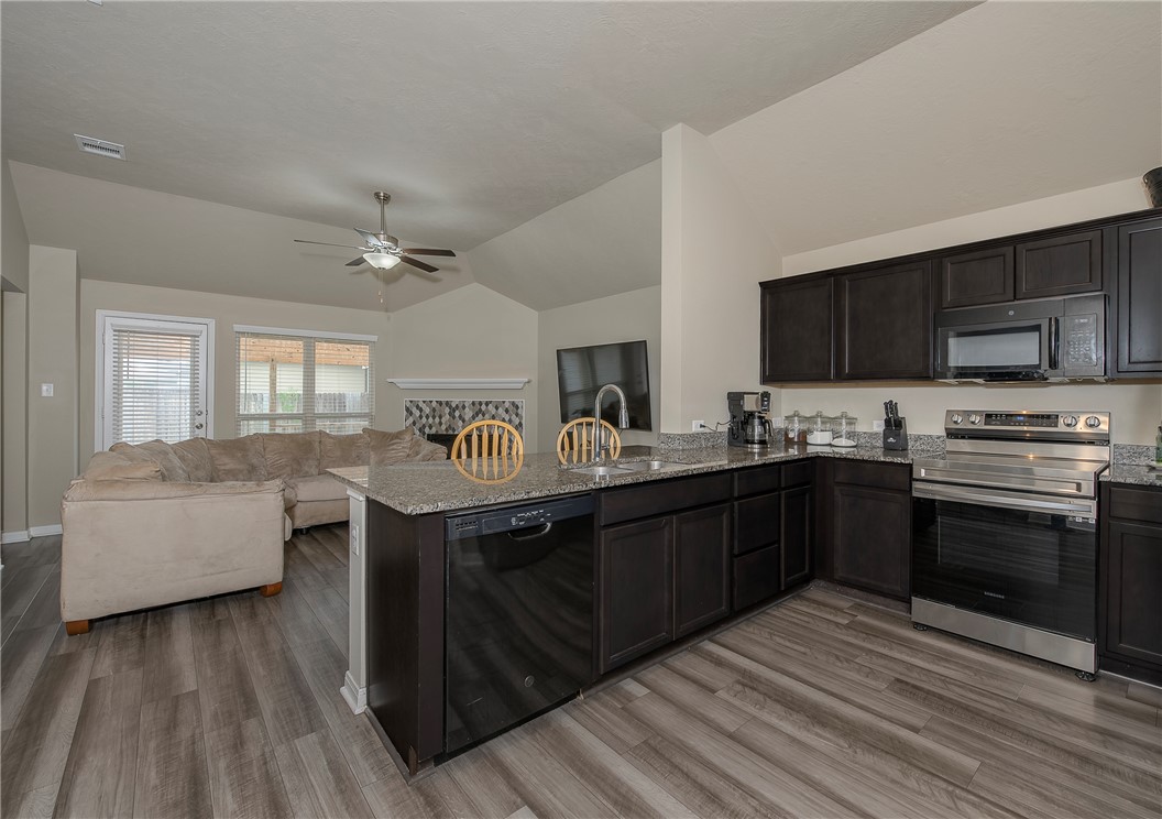 2702 Redcap Street Bryan, TX 77803 - Photo 4 of 17 a kitchen with stainless steel appliances granite countertop a sink dishwasher stove and oven with wooden floor