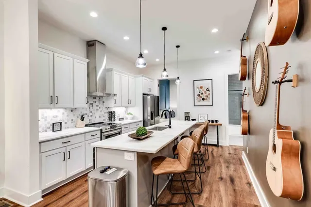 a kitchen with stainless steel appliances kitchen island a table chairs sink and stove top oven