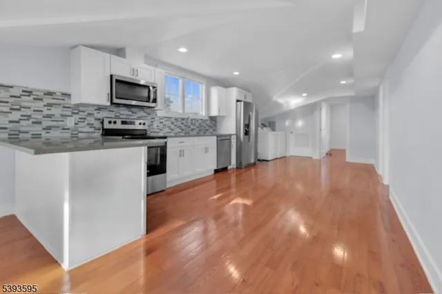 a large kitchen with stainless steel appliances granite countertop a sink and a microwave