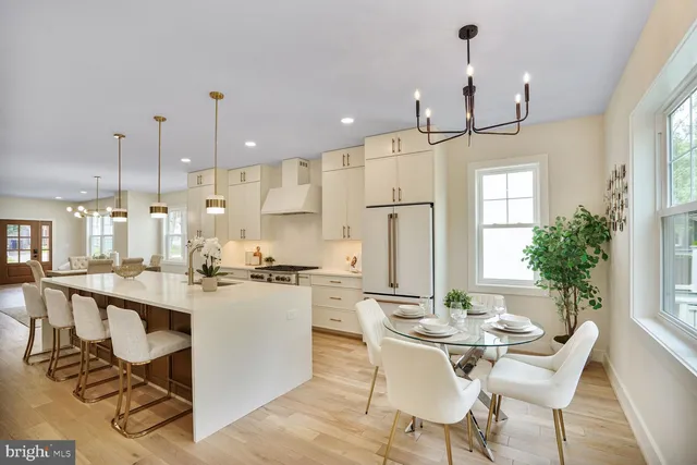 a kitchen with stainless steel appliances kitchen island a table chairs and a refrigerator