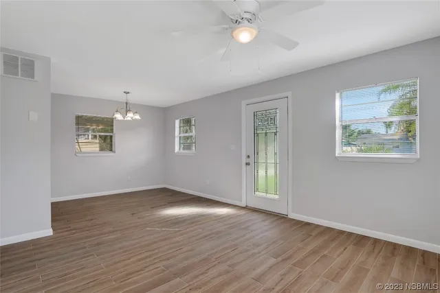 an empty room with wooden floor and windows
