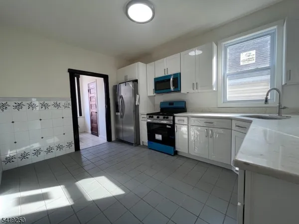 a kitchen with granite countertop a stove top oven sink and cabinets