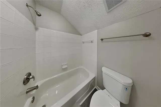 a white toilet and tub sitting next to a bathroom sink