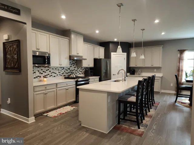 a kitchen with stainless steel appliances granite countertop a table chairs refrigerator and microwave