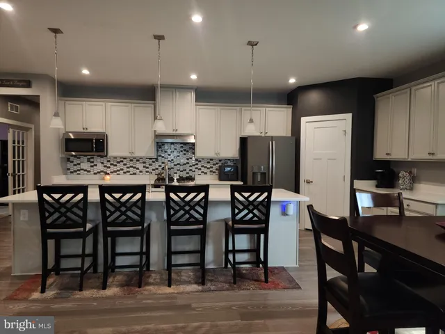 a view of a kitchen with kitchen island stainless steel appliances a stove a table and chairs