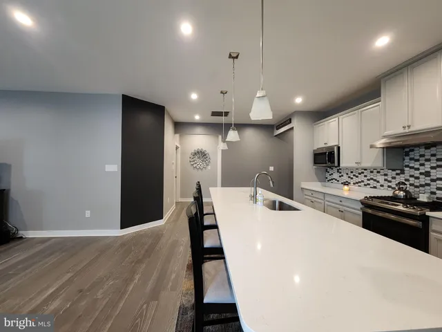 a kitchen with stainless steel appliances a sink a stove a refrigerator cabinets and a dining table