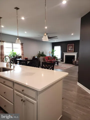 a kitchen with stainless steel appliances kitchen island granite countertop a stove a sink a refrigerator with white cabinets and wooden floor