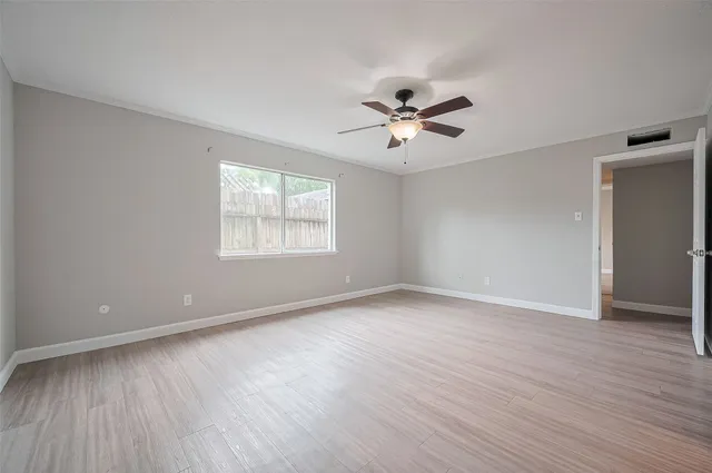 a view of empty room with wooden floor and fan