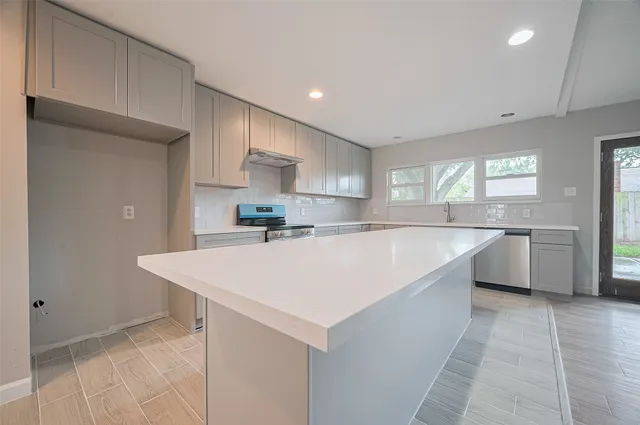 a large white kitchen with a sink a refrigerator and cabinets