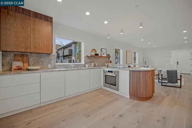 a view of kitchen with stainless steel appliances wooden floor and window