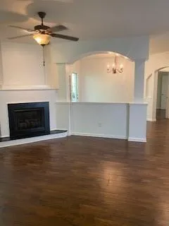 a view of an empty room with wooden floor fireplace and a window