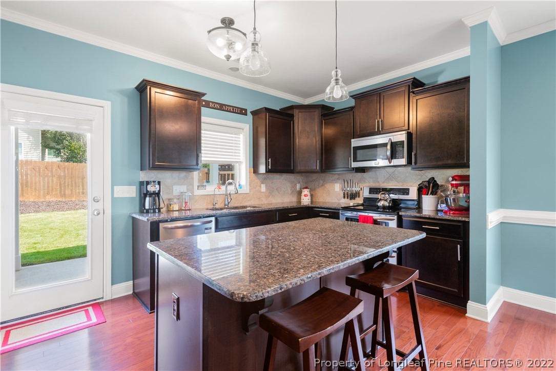 207 Samuel Nicholas Drive Cameron, NC 28326 - Photo 13 of 31 a kitchen with granite countertop a stove top oven a sink dishwasher a dining table and chairs with wooden floor