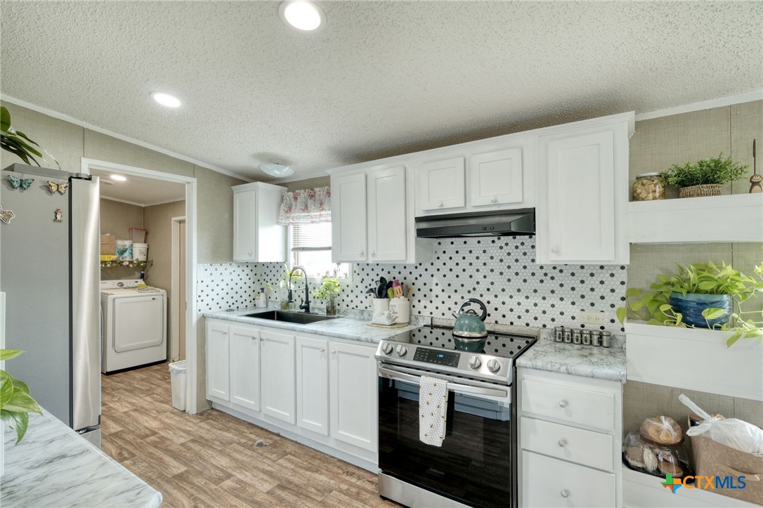 181 Pasadera Drive Elgin, TX 78621 - Photo 11 of 33 a kitchen with stainless steel appliances kitchen island granite countertop a sink and cabinets