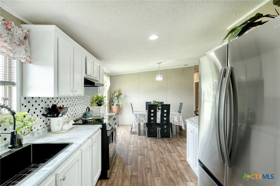 181 Pasadera Drive Elgin, TX 78621 - Photo 12 of 33 a kitchen with a sink stainless steel appliances a refrigerator and cabinets